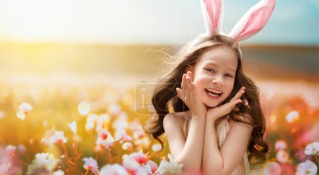Beautiful child outdoors. Celebrating Easter in nature. Cute little girl is wearing bunny ears.  