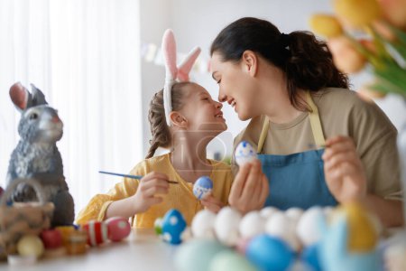 Téléchargez les photos : Mère et sa fille peignent des œufs. Bonne famille se préparant pour Pâques. Petite fille mignonne portant des oreilles de lapin. - en image libre de droit