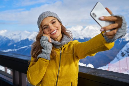 Photo for Technology and leisure concept - happy woman in winter fur hat taking selfie by smartphone outdoors - Royalty Free Image