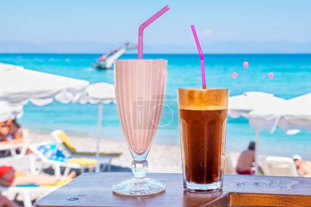 Photo for Glasses with milkshake and frappe on a table with view of the beach. Rhodes, Greece - Royalty Free Image