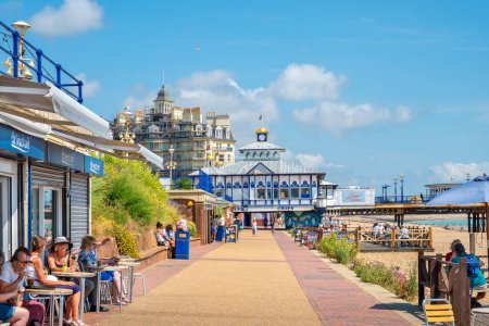 Photo for EASTBOURNE, ENGLAND - JULY 20, 2022: People rest on the Eastbourne boardwalk near the pier - Royalty Free Image