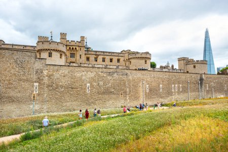 Photo for London, England - July 25, 2022: Tourists walk along dry moat around wall of the Tower of London - Royalty Free Image