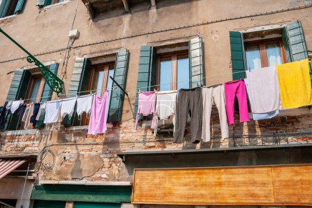 Téléchargez les photos : Des vêtements colorés accrochés à une corde à linge devant une vieille maison. Venise, Italie - en image libre de droit