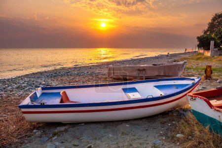 Rising sun illuminates boats on shores of Aegean Sea. Platamonas, Pieria, Greece