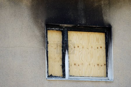 apartment window boarded up with plywood after a fire