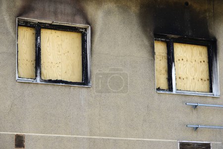 apartment windows boarded up with plywood after a fire