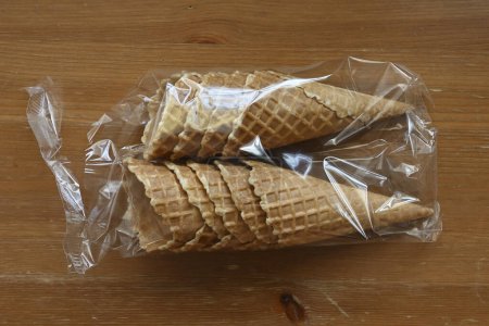 waffle cones in plastic packaging on a wooden table, ready to be filled with delicious ice cream 