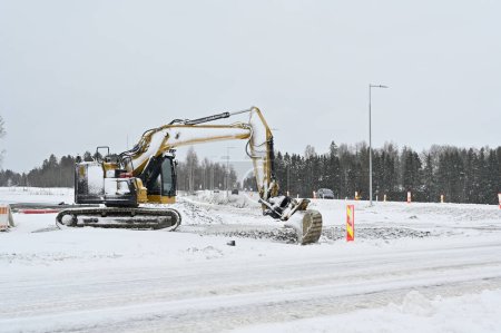 Ein Bagger arbeitet inmitten einer verschneiten Landschaft, räumt Schnee oder ist mit Bauarbeiten beschäftigt