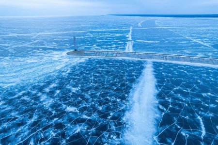 Photo for Aerial view of a lonely lighthouse in the frozen sea. Frozen blue ice in cracks, drone view - Royalty Free Image