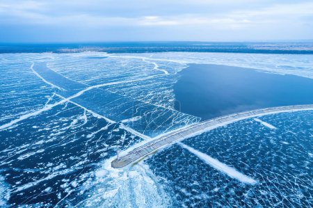Photo for Aerial view of a lonely lighthouse in the frozen sea. Frozen blue ice in cracks, drone view - Royalty Free Image