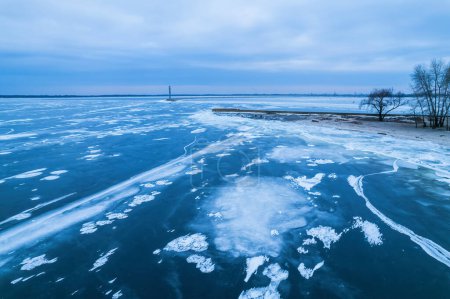 Téléchargez les photos : Brise-lames menant à la mer Baltique en hiver. Mer couverte de brouillard et de blocs de glace. Magnifique phare au lever du soleil. - en image libre de droit