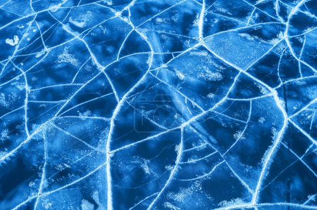 Téléchargez les photos : Glace sur une rivière gelée. Texture de fond de glace bleue avec des fissures dans la neige. vue de dessus de drone. - en image libre de droit