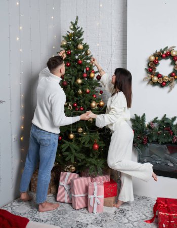 Téléchargez les photos : Couple décorant l'arbre de Noël avec le dessus d'étoile dans la chambre - en image libre de droit