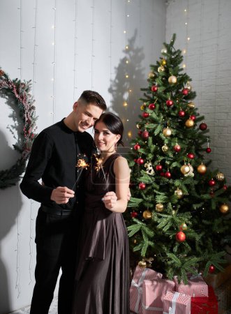 Téléchargez les photos : Beau couple amoureux. Joyeux jeune couple dans des vêtements élégants de soirée. Mode, glamour. Couple câlins à Noël intérieur décoré - en image libre de droit