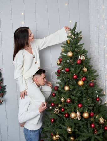 Foto de Joven pareja enamorada posando cerca del árbol de Navidad y abrazándose - Imagen libre de derechos