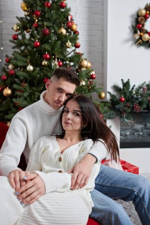 Foto de Joven pareja enamorada posando cerca del árbol de Navidad y abrazándose - Imagen libre de derechos