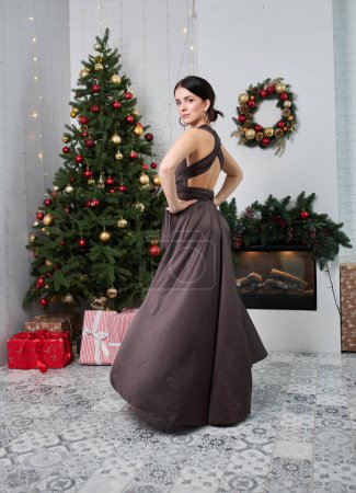 Téléchargez les photos : Belle femme élégante en robe de soirée noire sur l'arbre de Noël - en image libre de droit