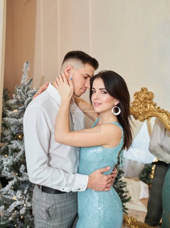 Photo for Beautiful couple in love. Cheerful young couple in elegant evening clothing. Fashion, glamour. Couple hugging in christmas decorated interior - Royalty Free Image