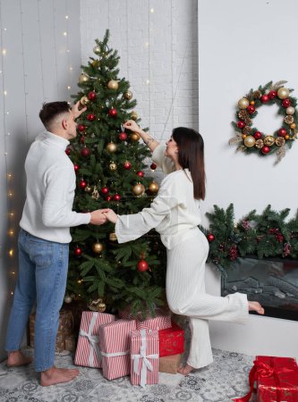 Téléchargez les photos : Couple décoration arbre de Noël dans la chambre - en image libre de droit