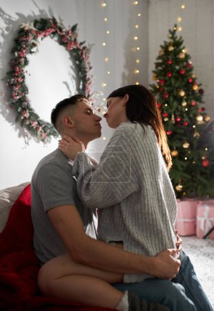 Téléchargez les photos : Jeune couple amoureux posant près du sapin de Noël et étreignant - en image libre de droit