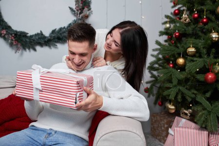 Téléchargez les photos : Joyeux jeune couple échangeant des cadeaux de Noël le matin de Noël - en image libre de droit