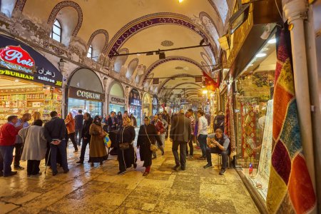 Téléchargez les photos : ISTANBUL - APRIL 21, 2017: People shopping in the Grand Bazar, handmade pillows, bags and carpets are on the wall for sale. - en image libre de droit