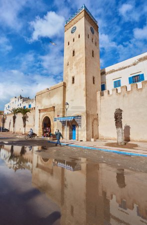 Téléchargez les photos : ESSAOUIRA, MOROCCO. 13 th February, 2017: Ancient walls of the medina, merchants hurrying on business, after the rain - en image libre de droit