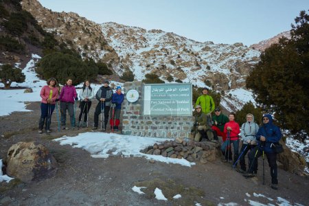 Foto de Toubkal national park, Morocco, 07 th February, 2017: A group of tourists near the entrance sign to Toubkal National Park in Morocco - Imagen libre de derechos