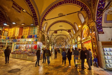 Foto de ISTANBUL - APRIL 21, 2017: People shopping in the Grand Bazar, handmade pillows, bags and carpets are on the wall for sale. - Imagen libre de derechos