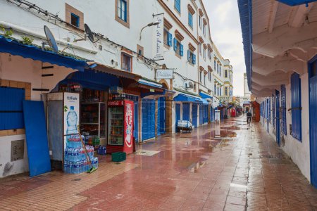 Téléchargez les photos : ESSAOUIRA, MOROCCO. 12 th February, 2017: Streets of the old city, Medina, colorful houses. People rushing to work, the city after the rain - en image libre de droit