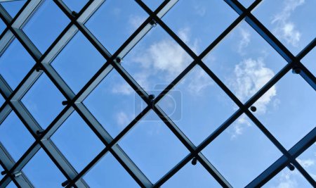 Téléchargez les photos : Below view of glass roof consisting of square and triangle segments with sky visible through - en image libre de droit