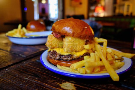 Téléchargez les photos : Grand hamburger savoureux et frites avec de la bière sur fond sur la table en bois - en image libre de droit