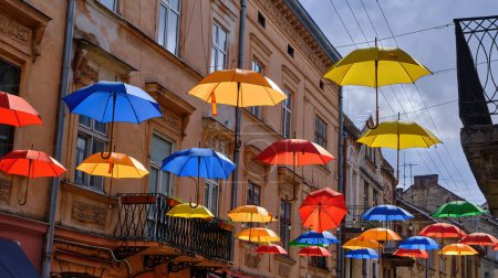 Foto de Romantically decorated with the umbrellas hanging from the wires on the narrow street of the old city - Imagen libre de derechos