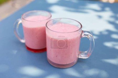 Foto de Two pink fruit and milkshakes in glass cups stand on a table in a cafe on the street - Imagen libre de derechos
