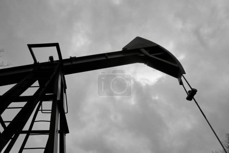 Photo for An abandoned oil or gas rocking machine against a blue sky, exhausted resource. A clogged field of gas and oil production. - Royalty Free Image