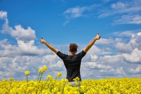 Photo for Happy man stands in a yellow field rejoicing raises his hands to the sky. - Royalty Free Image