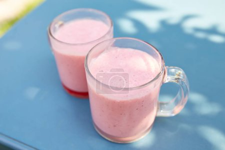 Foto de Two pink fruit and milkshakes in glass cups stand on a table in a cafe on the street - Imagen libre de derechos
