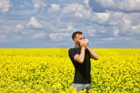 Foto de Man in field blowing his nose and suffering from hay fever. Allergy - Imagen libre de derechos