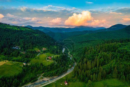 Photo for Scenic aerial view of the foggy Carpathian mountains, village and blue sky with sun and clouds in morning light, summer rural landscape, outdoor travel background - Royalty Free Image