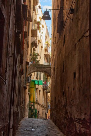 Photo for Naples, Italy - October 25, 2019 - Residents walk between cars parked on a narrow laundry-lined street of the historic Centro Storico city center. - Royalty Free Image
