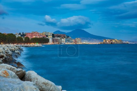 Téléchargez les photos : Castel dell Ovo Château d'Egg à Naples, Italie, vue depuis le quai en lumière bleue du soir - en image libre de droit