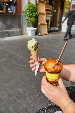 Photo for Holding gelato ice-cream cone with mint pistachio colour in the city. Summer cold refreshment. Delicious food. - Royalty Free Image