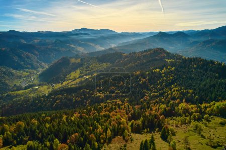 Photo for Mountain forest landscape under evening sky with clouds in sunlight. Aerial drone view. - Royalty Free Image