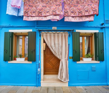 Foto de Una encantadora casa europea, con dos ventanas, flores colgantes y persianas rojas - Imagen libre de derechos