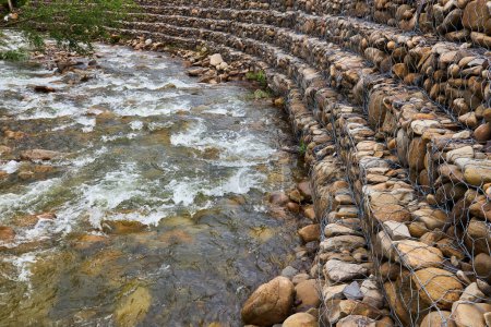 Photo for Strengthening the banks of the mountain river, mesh and stones. Landscape river bank and large stones with metal mesh - Royalty Free Image
