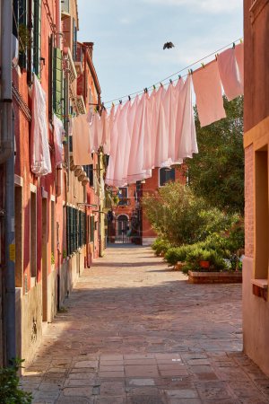 Photo for Laundry put to dry on a small traditional and very colorful place on the island of Burano, Italy. - Royalty Free Image