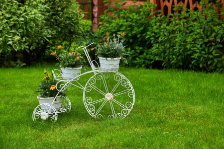 Photo for Model of an old bicycle equipped with basket of flowers. Bicycle in a garden - Royalty Free Image