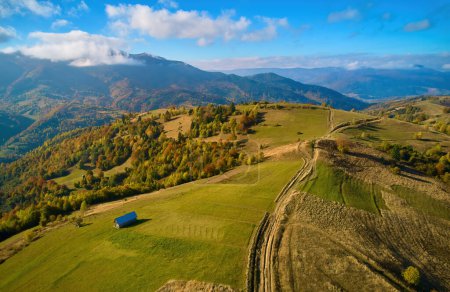 Photo for Aerial view of mountains at sunrise in autumn in Ukraine. Colorful landscape with mountain road, forest, houses on the hills, sunlight, sky in fall. Top view of roadway and village - Royalty Free Image