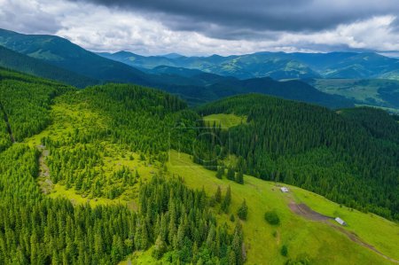 Photo for Scenic aerial view of the foggy Carpathian mountains, village and blue sky with sun and clouds in morning light, summer rural landscape, outdoor travel background - Royalty Free Image