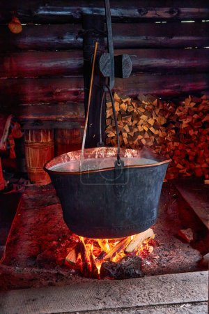 Foto de Making organic sheep cheese in wooden mountain Carpathian cheese factory with a boiling smoked cauldron with milk on open fire, Western Ukraine, Europe - Imagen libre de derechos